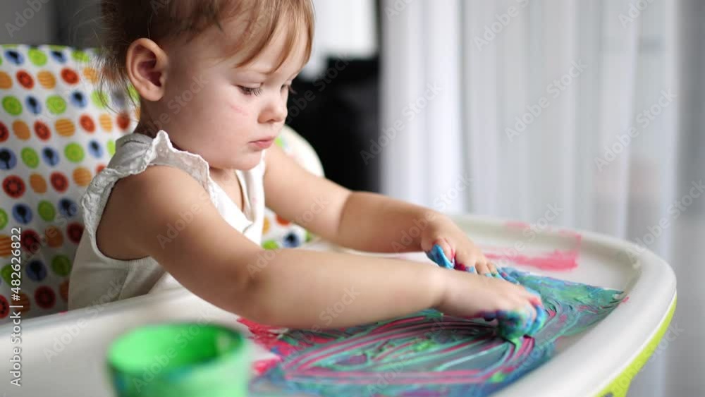 Cute little girl painting with fingers at home. Creative games for kids. Stay at home entertainment Cute little girl painting with fingers at home. Creative games for kids. Stay at home entertainment