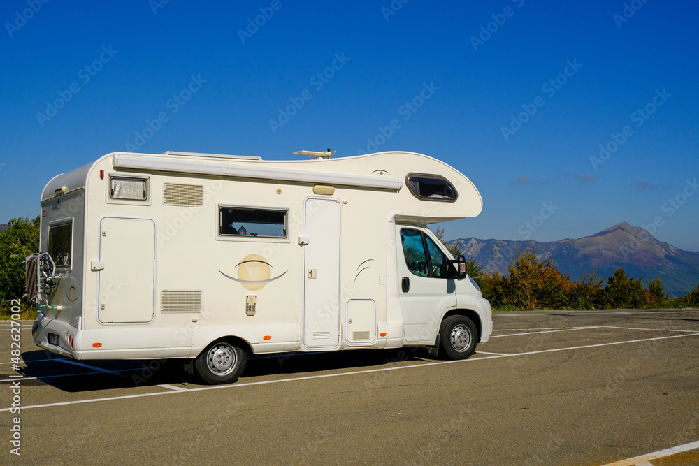 camper van on the road across blue sky and mountains peaks. Adventurous lifestyle. Camper life. Travel in mountains camper van on the road across blue sky and mountains peaks. Adventurous lifestyle. Camper life. Travel in mountains