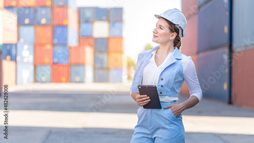 CEO or Manager Woman in white helmet control loading Containers box in warehouse , manager inspector or Safety Supervisor in Container CustomTerminal port concept import export transportation