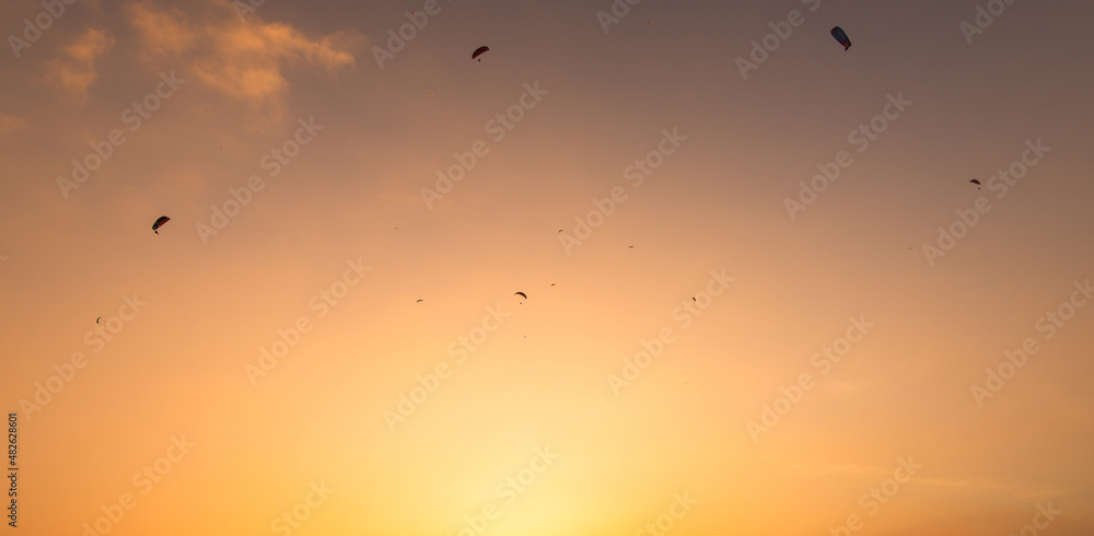 Air sports background. Parachutes in the orange sky. Sky sports at sunset.