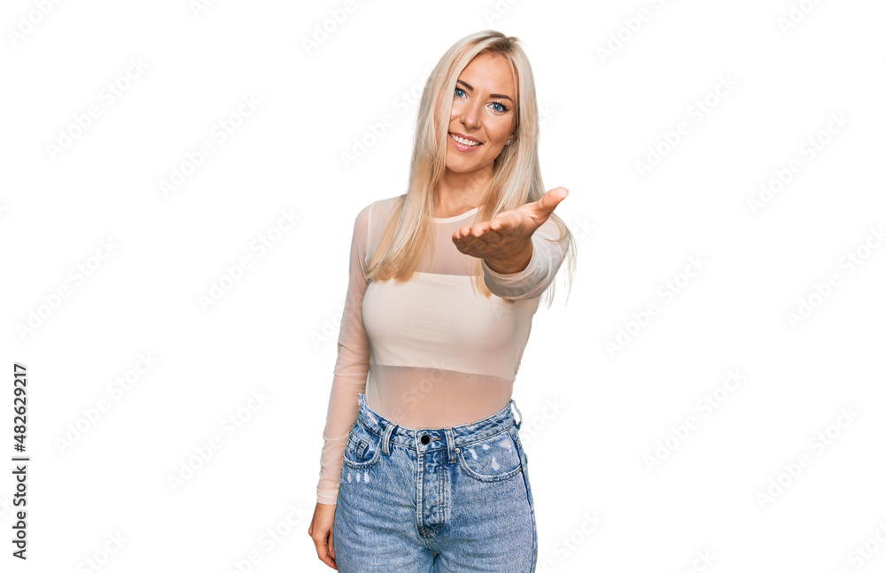 Young blonde woman wearing casual clothes smiling friendly offering handshake as greeting and welcoming. successful business. Young blonde woman wearing casual clothes smiling friendly offering handshake as greeting and welcoming. successful business.