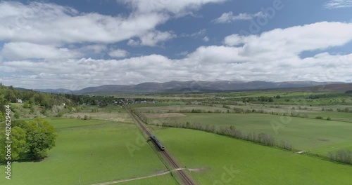Aerial follow shot of a Scotrail Train heading towards Newtonmore in Scotland photo