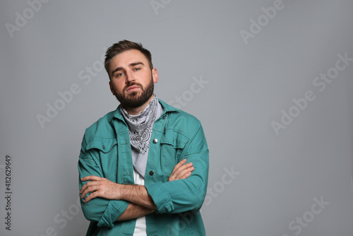 Fashionable young man in stylish outfit with bandana on grey background, space for text