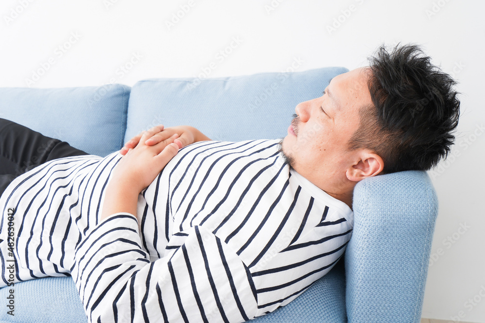 自宅で昼寝をする中年の男性