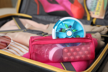 Pouch with different medicaments and pill box in packed suitcase, closeup