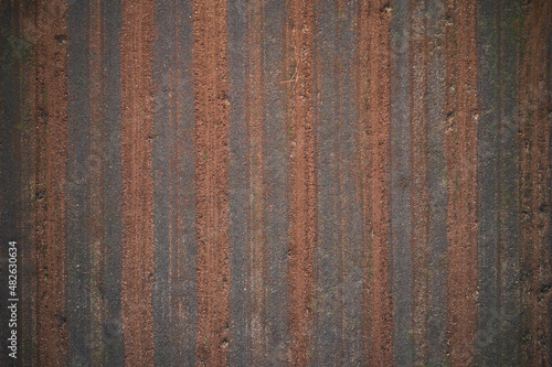 Italian arable land in winter season top view. Striped texture brown red color aerial view. Texture of arable land top view. Winter texture plowed land drone view.