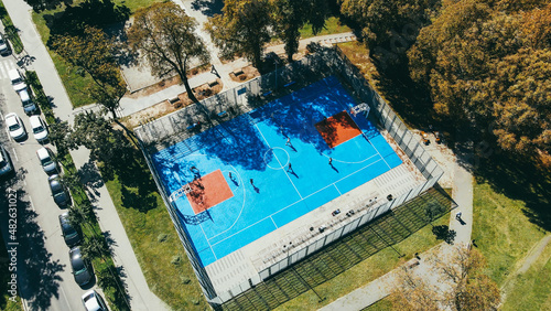 Aerial view of the blue stadium in the park, teenagers playing basketball