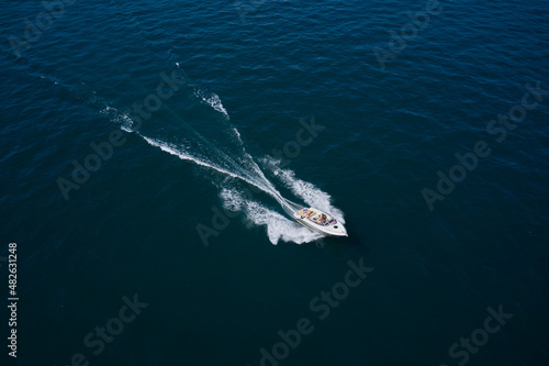 Boat drone view. Speedboat moves fast on the water view from above. Big white boat with people in motion in the sea top view. © Berg