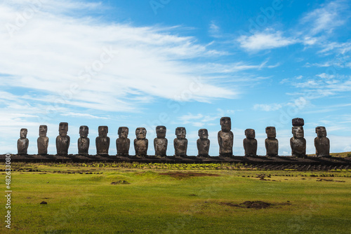 The fifteen moais of the Ahu Tongariki from the front with the green meadow in front and the sunny sky with clouds on Easter Island photo