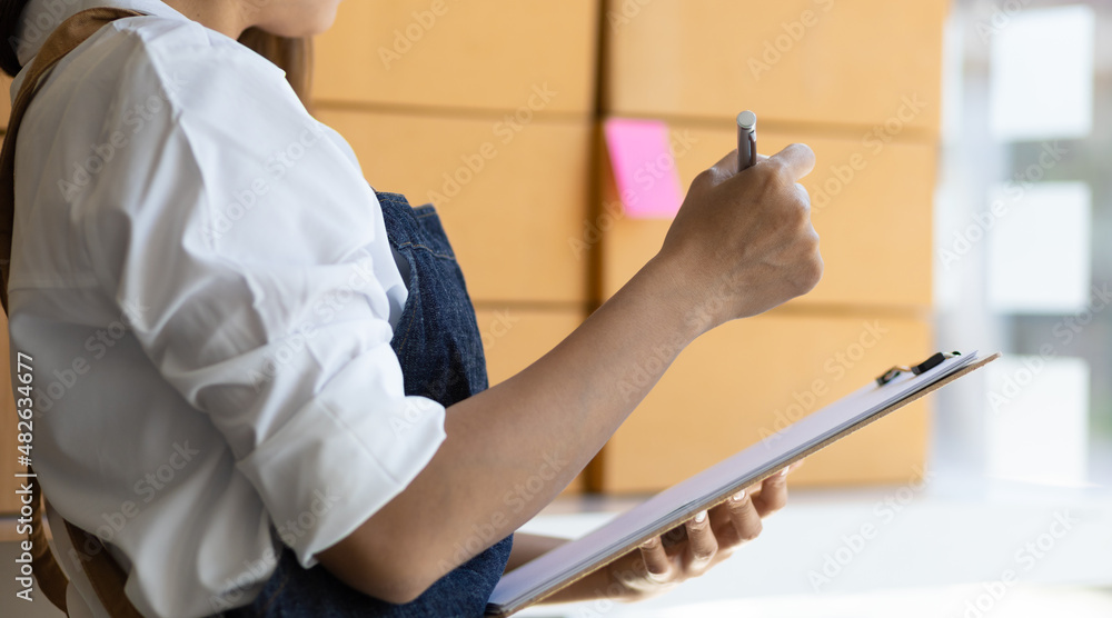 Small business owner woman holding a notepad with a list of items and orders.