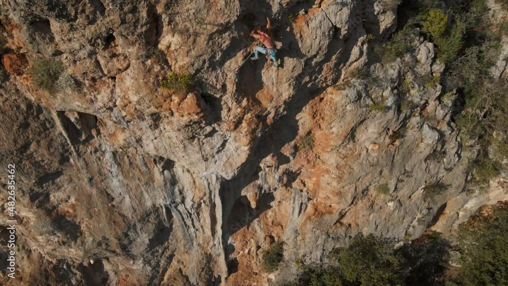 aerial drone POV of strong muscular man climbing challenging route on vertical crag with tufa. climber reaches handholds and makes long hard movement and effort. High quality 4k slow motion footage aerial drone POV of strong muscular man climbing challenging route on vertical crag with tufa. climber reaches handholds and makes long hard movement and effort. High quality 4k slow motion footage