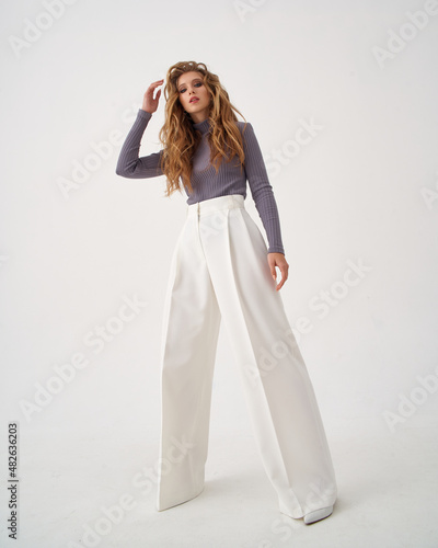 Принти на полотні Blonde young woman with stylish hairstyle in knitted sweater and white trousers