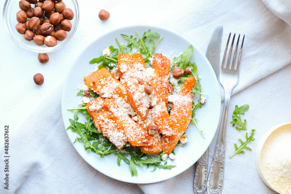 Healthy vegan balanced Salad of baked pumpkin, arugula, parmesan and hazelnuts. View from above. Healthy vegan balanced Salad of baked pumpkin, arugula, parmesan and hazelnuts. View from above.