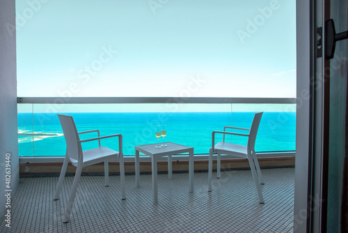 Romantic vacation cocnept. Two wine glass eson the table in hotel balcony with sea view in  tropical country.