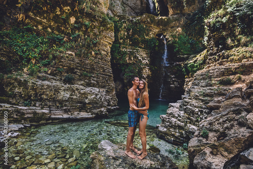 Loving Couple in Swimsuits Hugging at Waterfall