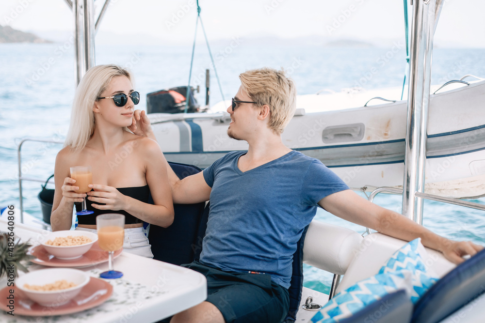 Portrait of two gentle affectionate people boyfriend and girlfriend spending time with each other and relaxing, sailing on a yacht and having dinner on the background of another yacht and water
