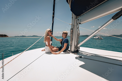 Adorable carrying and fell in love guy and girl sitting on a yacht and discussing something very interesting enjoying moments and each other's company against the backdrop of water and nature.
