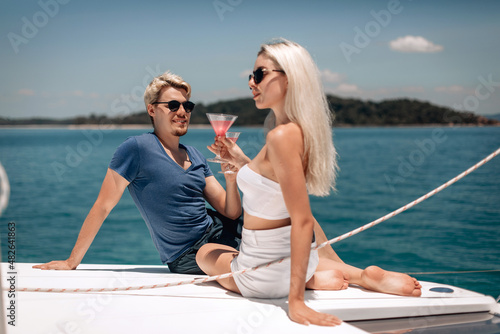 Aesthetic young and attractive female and male models with blond hair having fun outdoors, holding cocktails in crystal glasses. Beauty concept © Semachkovsky 