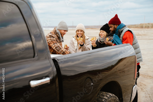 Multiracial friends smiling and eating sandwiches during car trip