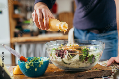 Bilde på lerret close up man dressing salad. preparing food in his kitchen