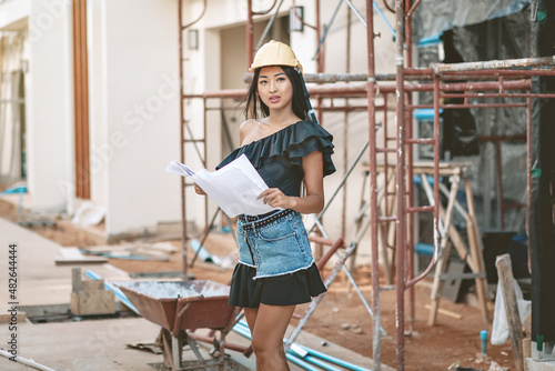 Business girl engineer is overseeing work at a construction site, holding a project in his hands