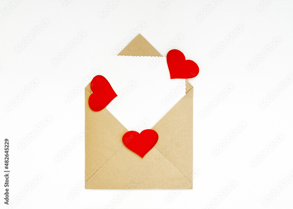 Kraft envelope with a white note sheet and red hearts on a white background. The concept of Valentine's day, love, anniversary. copy space