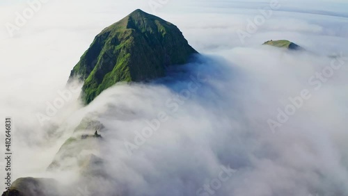 Awesome aerial panorama. High green ridge covered with dense white clouds around