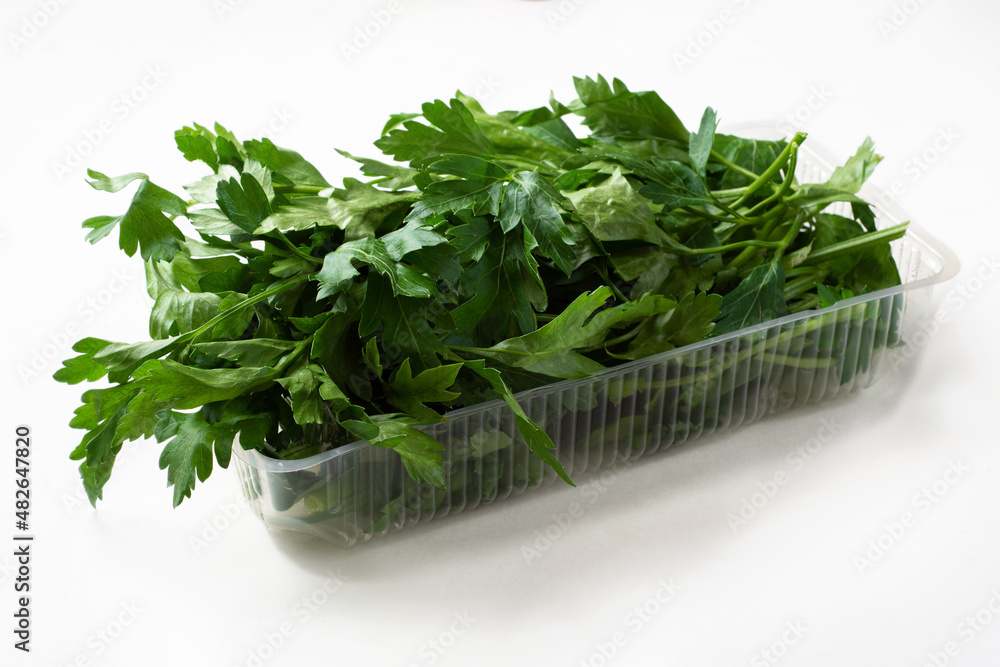 Fresh parsley in plastic packaging on a white background. Fresh herbs in a package Fresh parsley in plastic packaging on a white background. Fresh herbs in a package