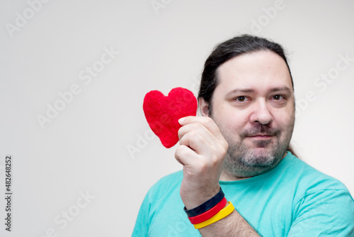 Fotografie An adult, unshaven man holds a red heart in his hand