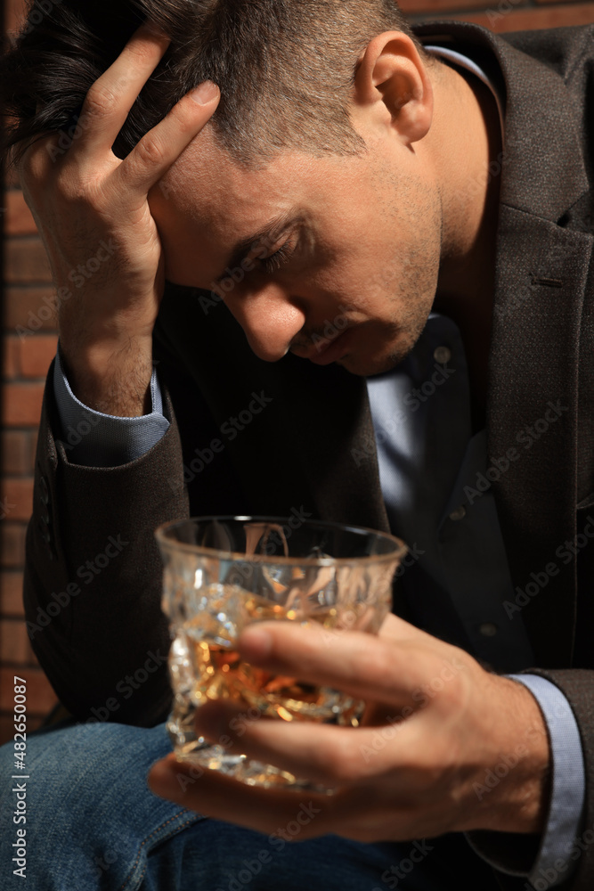 Addicted man with glass of alcoholic drink near red brick wall, closeup Addicted man with glass of alcoholic drink near red brick wall, closeup
