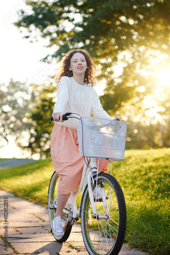 Girl in pinky skirt with a bike in the park