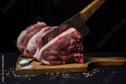 Pork meat on a black background. Meat loin with bone on a wooden board. Meat cooking	