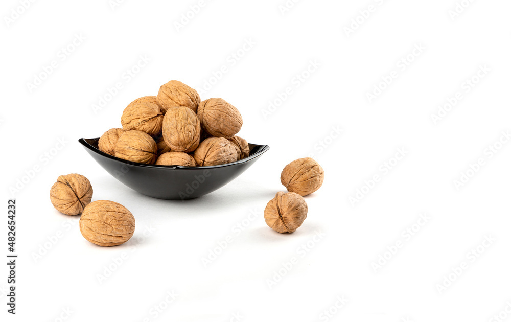 Walnuts in a dark plate on a white background.Copy space. Walnuts in a dark plate on a white background.Copy space.