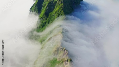 Awesome overhead panorama. Dense white clouds crawl over green mountains range