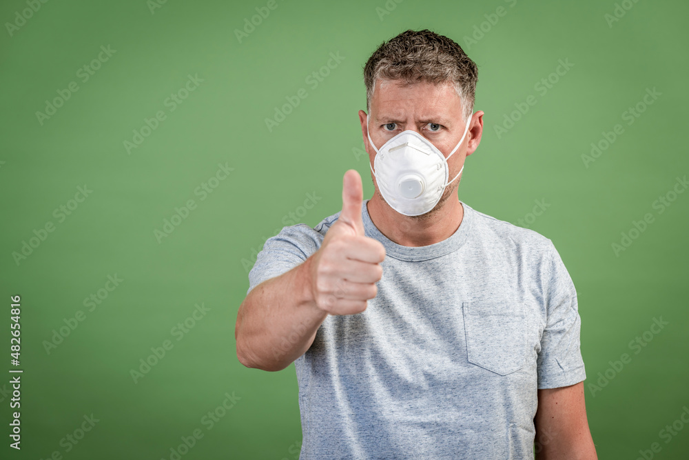 man with ffp2 nose and mouth mask standing in front of green background man with ffp2 nose and mouth mask standing in front of green background