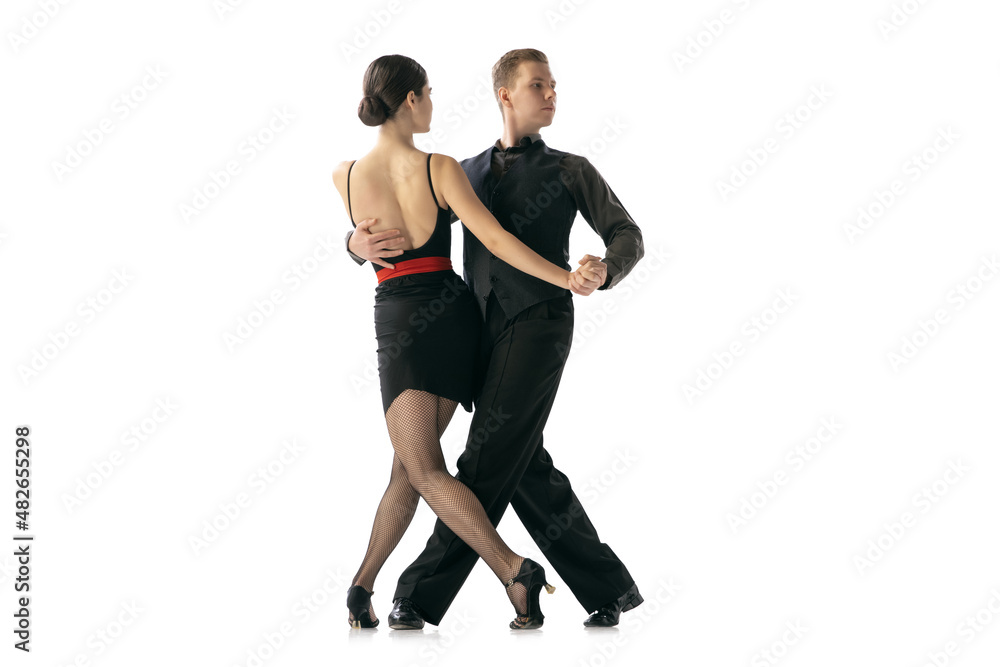 Flexible young couple dancing Argentine tango isolated on white studio background. Artists in black stage costumes Flexible young couple dancing Argentine tango isolated on white studio background. Artists in black stage costumes