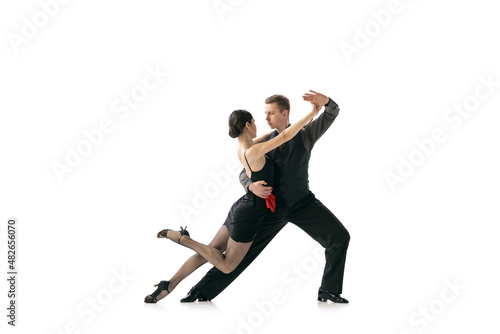 Dynamic portrait of flexible young dancers dancing Argentine tango isolated on white studio background. Artists in black stage costumes