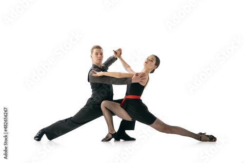 Grace and beautiful dancers, young couple dancing Argentine tango isolated on white studio background. Artists in black stage costumes