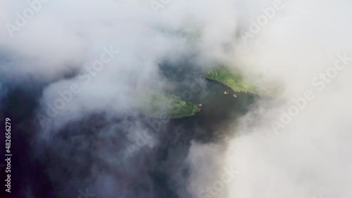 Aerial panorama. Dense white clouds cover dark water pond with green shoreline