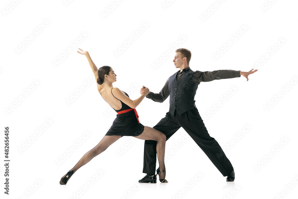 Flexible young couple dancing Argentine tango isolated on white studio background. Artists in black stage costumes Flexible young couple dancing Argentine tango isolated on white studio background. Artists in black stage costumes