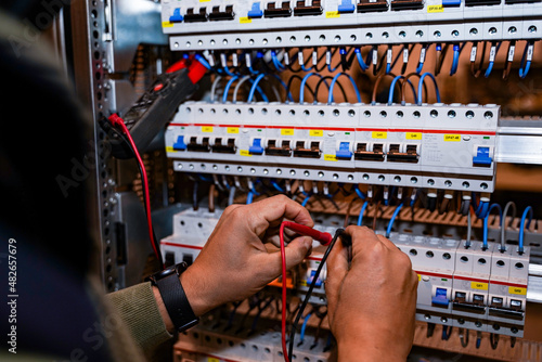 Electrician performing power tests on switches and differentials for the light of an industrial electrical panel.