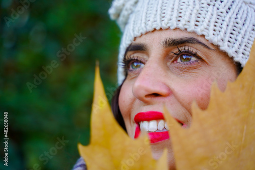 Close-up portrait of young elegant woman in autumn season with a leaf.