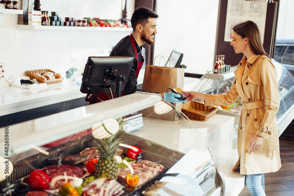 Young woman paying credit card for purchases in grocery store. Young woman paying credit card for purchases in grocery store.