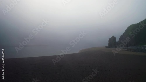 Circle panorama. Flight above deserted sand beach with rocky green hills in mist