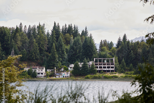 Abandoned and destroyed buildings on a lake in Argentine Patagonia. Old buildings among pine trees and on the shores of the lake.