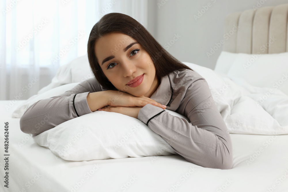 Beautiful young woman lying on bed at home Beautiful young woman lying on bed at home