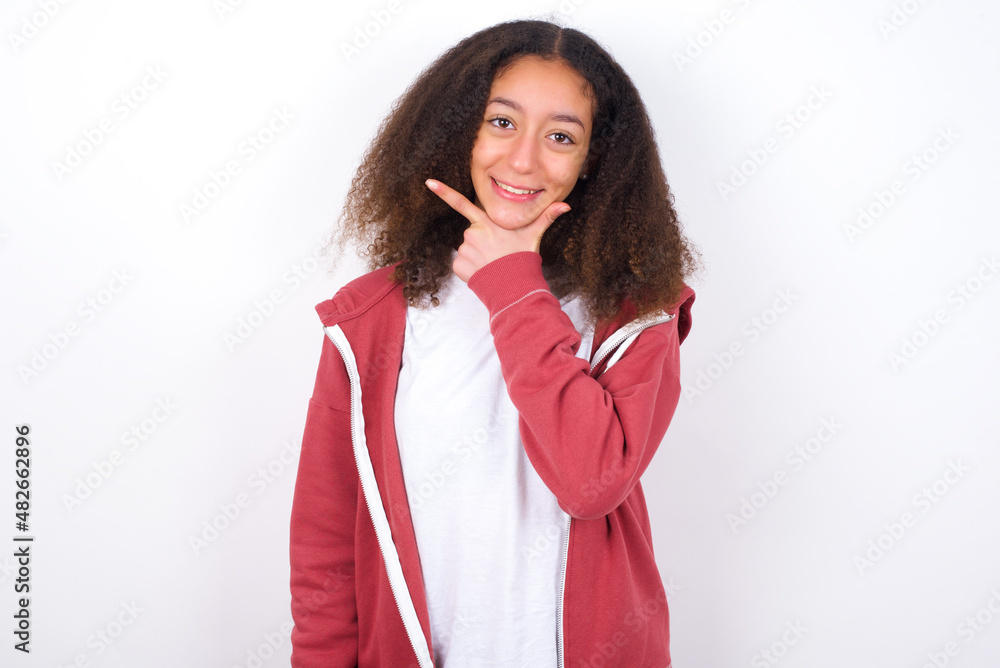 teenager girl wearing pink jacket standing against wite background looking confident at the camera smiling with crossed arms and hand raised on chin. Thinking positive. teenager girl wearing pink jacket standing against wite background looking confident at the camera smiling with crossed arms and hand raised on chin. Thinking positive.