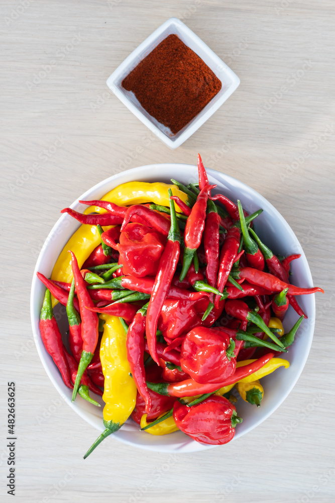 Mixed hot chili peppers in bowl and ground peppers in small jar Mixed hot chili peppers in bowl and ground peppers in small jar
