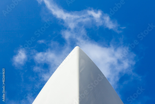 Fototapeta The bow of a white yacht, against a blue sky with white clouds