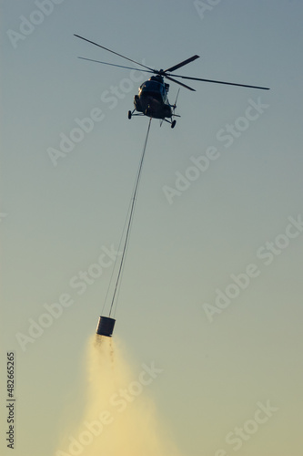Military helicopter putting out forest fire in Istria Croatia at sunset